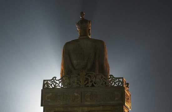 Backlit Asian statue at night.