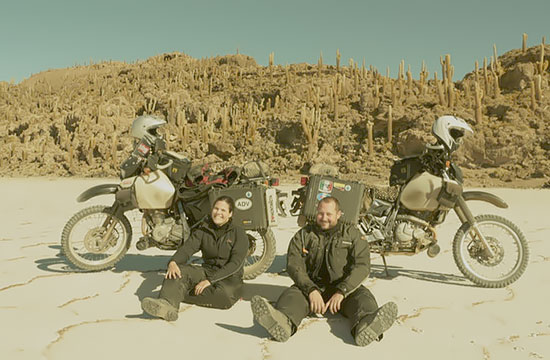Jenn Page and Adam Tworkowski, sitting in the sand with the bikes.