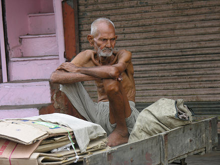 Old man sits on his cart waiting for scrap cardboard