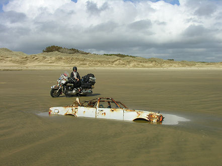 Cars half buried in sand, slowly rusting away