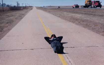 Greg laying on the road, Route 66, next to Interstate 40, with no worries