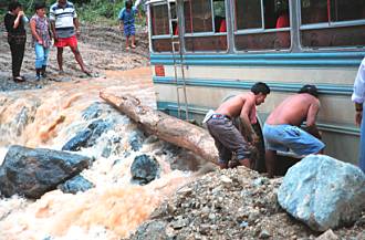 There's a man underneath the bus, clearing rocks.