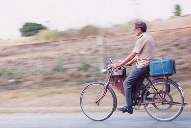 Cuban man on bicycle with motor and belt drive.