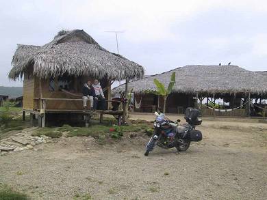 The honeymooners in front of our beachfront cabin in Ecuador with the bike nearby.