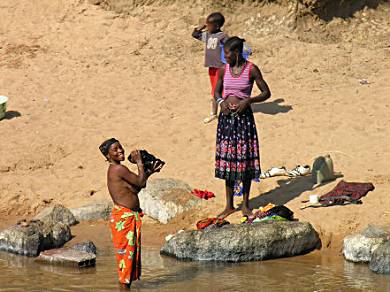 Ladies washing themselves and their clothes riverside.