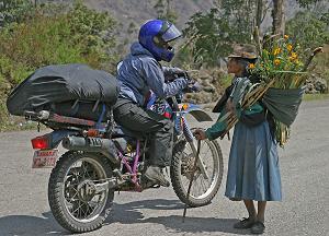 June: by Todd Lawson, Canada; of Christina Tottle from Canada; chatting with a friendly local, complimenting her hand-picked bouquet, La Moya, Ecuador, Latin American odyssey. Yamaha XT 350.