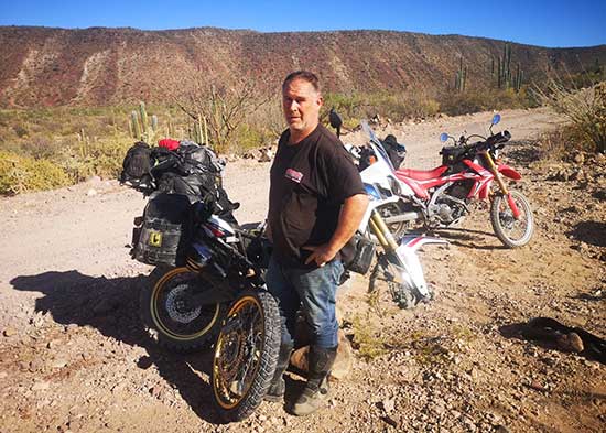 Scott fixing a motorcycle tire on a dirt road