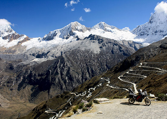 Pau Saunders, motorcycle in foreground with snowy mountain range beyond.l