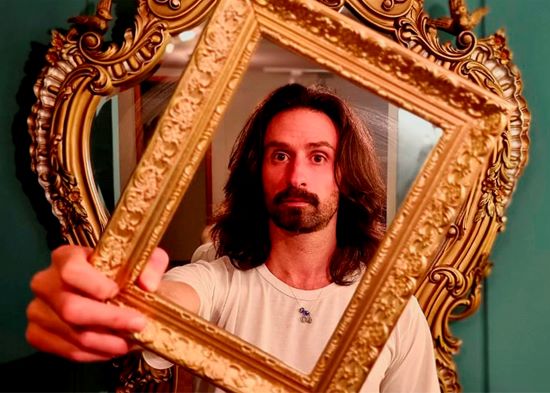 Nico Lazlo, Comedian reflected in an ornate picture frame.