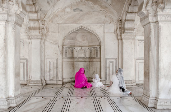 Women sitting in front of a marble alcove.