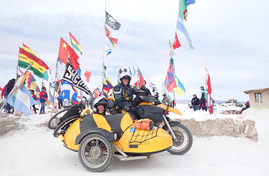 Heike and Toshi. Sidecar in the snow with colourful flags all around.