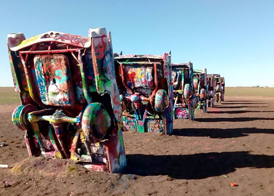 Graffiti'd upturned cars line the side of a section of Route 66, USA.