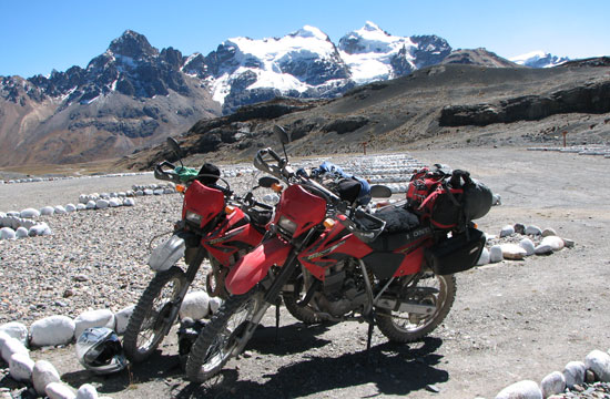 Two bikes and mountain backdrop.