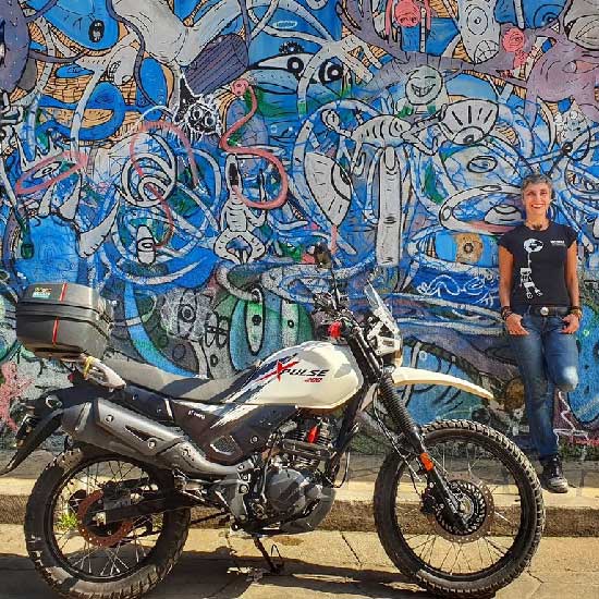 Mahsa Homayounfar and bike in front of a graffiti'd wall, Central America