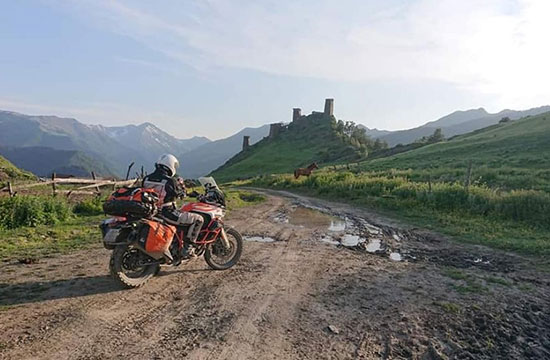 Motorcyclist approaches a horse near some ruins