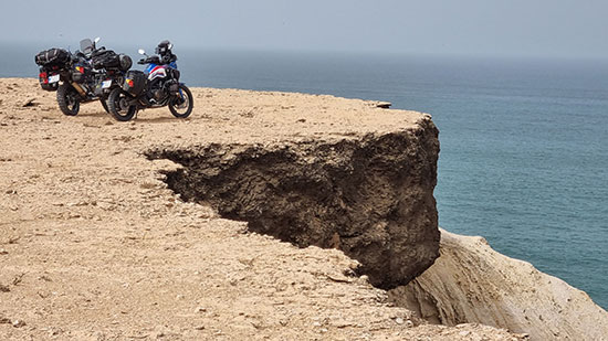 Radu Prie. Two Africa Twin motorcycles overlooking water from a high bluff.