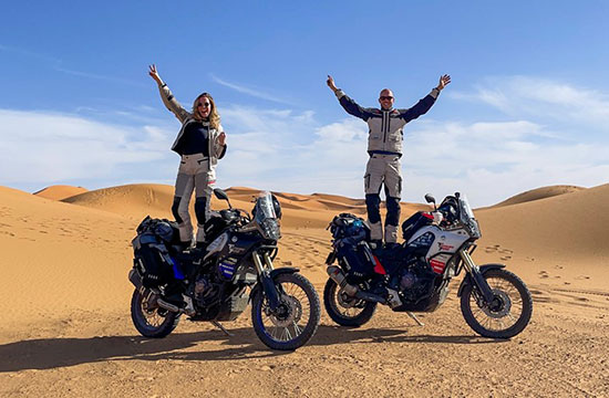 Jessica Gelderman and Maarten Molenberg standing on their motorcycles in the desert