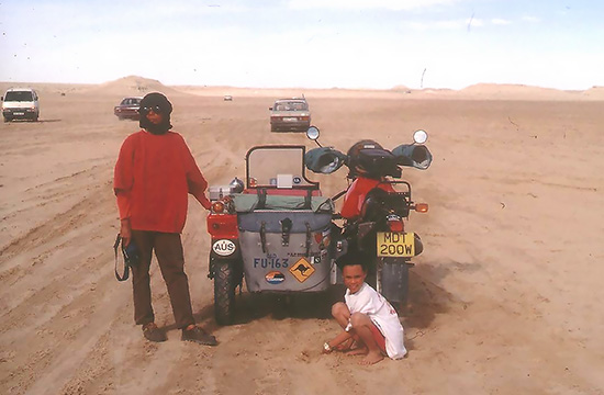 Emy and David Woodburn family traveling across a desert in a sidecar