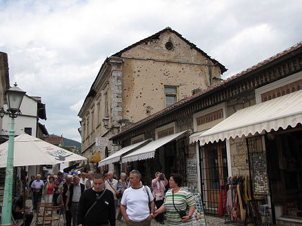 Bullet holed building above reconstructed tourist path in Mostar