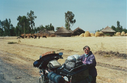 Grass hut village, cattle and haystacks along the roadside