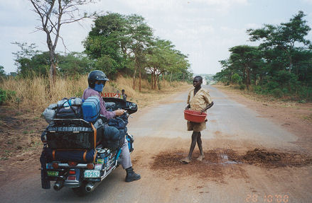 Young boy repairing pot holes hoping for some money