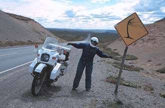 Susan and bike beside a sign stating the obvious on the road north in Tierra del Fuego.