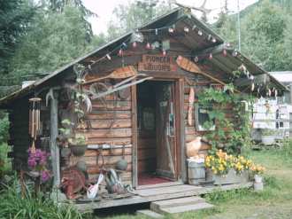 Modern Christmas lights vie for attention with pioneer antiques on cabin in Alaska.