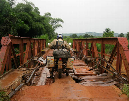 by Mark Hammond, USA. Geoff Shingleton, UK pauses on a war-ravaged bridge west of Mindouli, Republic of Congo, Morocco to Cape Town ride, Yamaha XT600.